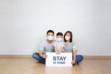 Asian family wearing protective medical mask for prevent virus Covid-19 holding white paper with...