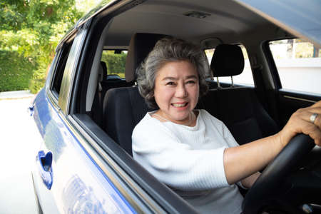 Asian senior woman driving a car and smile happily with glad positive expression during the drive to...