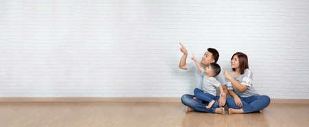Asian family pointing with finger towards something empty copyspace
