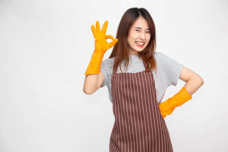 Portrait of young Asian woman wearing orange rubber gloves for hands protection during cleaning and showing ok sign isolated over white backgroundの写真素材