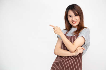 Portrait of Asian woman workers fresh market with brown apron standing and pointing finger to something isolated on white backgroundの写真素材