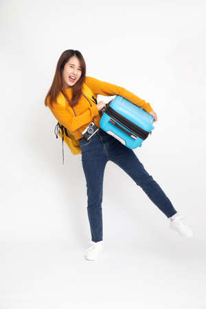 Young Asian woman traveler with backpack standing and holding suitcases isolated on white background
