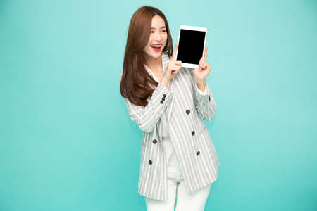 Happy asian woman smile and holding tablet isolated over light green background