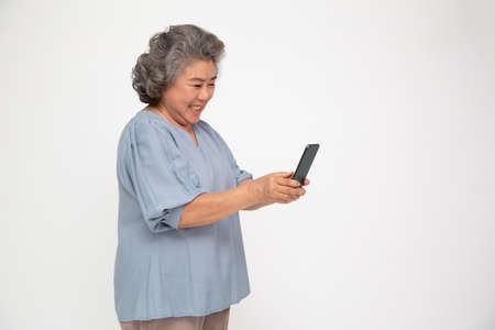 Asian senior woman using smartphone and receiving good news from the message on mobile chat application isolated over white backgroundの写真素材