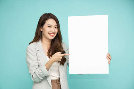 Asian business woman showing and holding blank white billboard isolated on green backgroundの写真素材