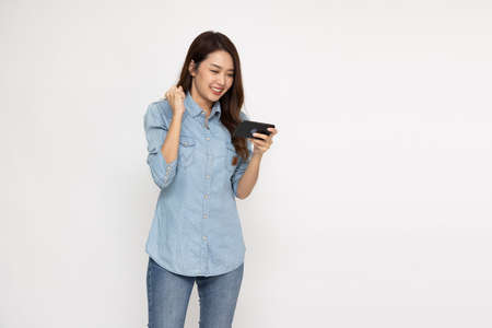 Cheerful Asian woman using smartphone and receiving good news from the message on mobile chat...