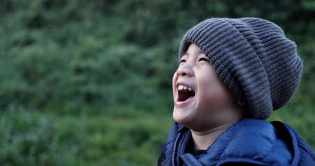 Asian boy wearing wool hat and laughing in winter seasonの写真素材