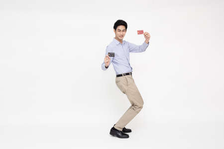 Young Asian man smiling, showing, presenting credit card for making payment or paying online...