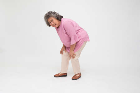 Senior Asian woman suffering from knee pain isolated on white background, Arthritis disease or Osteoarthritis conceptの写真素材