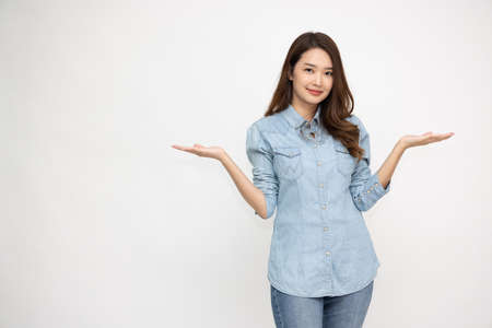 Happy Asian woman wearing jeans shirt and presenting, showing open hand palm with copy space for product isolated on white backgroundの写真素材