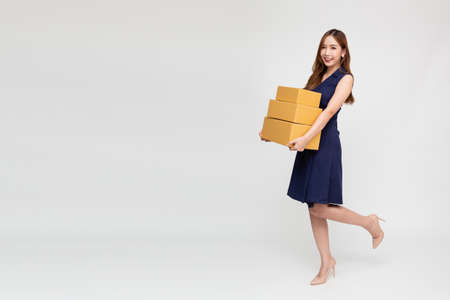 Happy Asian woman smiling and holding package parcel box isolated on white background, Delivery courier and shipping service concept, Full body compositionの写真素材