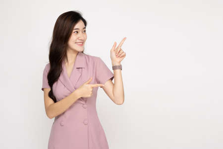 Young Asian woman smiling and pointing to empty copy space isolated on white backgroundの写真素材
