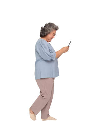 Happy Senior Asian woman typing on mobile phone and walking isolated on white background, Full body compositionの写真素材
