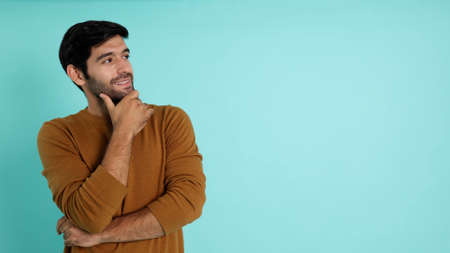 Handsome happy young man smiling and looking sideways to empty copy space isolated on light green studio backgroundの写真素材