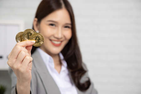Close up hand of Young Asian businesswoman in suit showing golden bitcoin BTC cryptocurrencyの写真素材