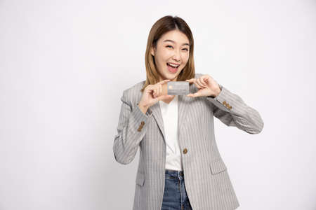 Young beautiful Asian businesswoman in suit smiling, showing, presenting credit card isolated on white backgroundの写真素材