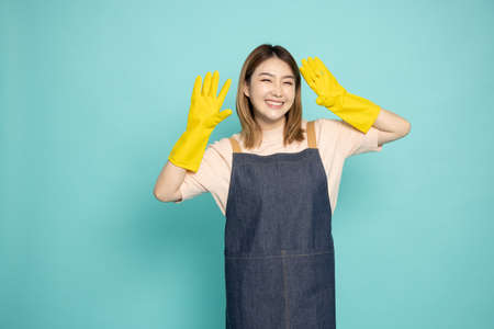 Portrait of Happy Young Asian woman maid or housewife wearing rubber gloves isolated on green backgroundの写真素材