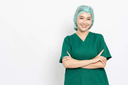 Confident smiling Asian doctor woman, Nurse in scrubs outfit standing with cross arms isolated over white backgroundの写真素材