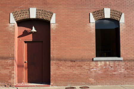 Red brick wall with a wooden door and a window in the foregroundの写真素材