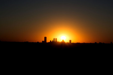 Silhouette of a city at sunset with the sun in the skyの写真素材