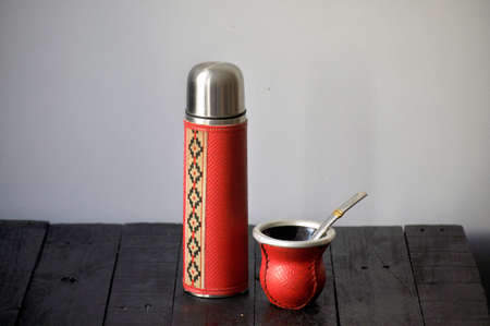 Argentinian mate on a black counter. They are aluminum and the cover is a gaucho design. The mate is...