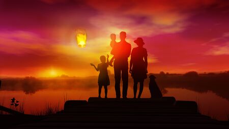 Family with children watches on launched Chinese lantern at sunsetの写真素材