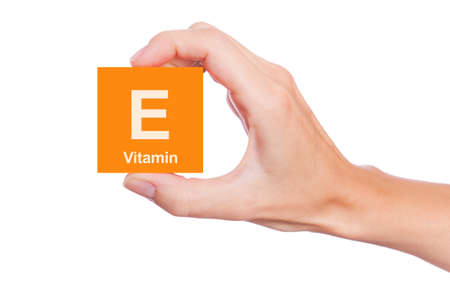 Hand that holds a box of Vitamin E isolated on white backgroundの写真素材