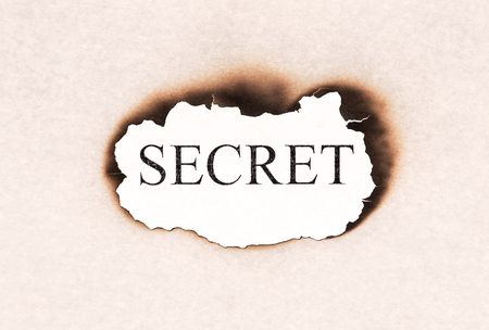 Secret revealed word text appearing behind burned paperの写真素材