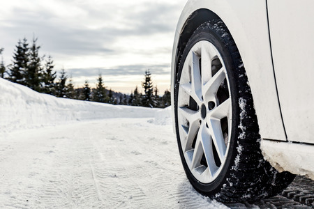 The wheel of a car on a snowy mountain road in the cold winterの写真素材