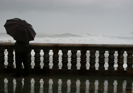 A man with an umbrella looking at the stormの写真素材