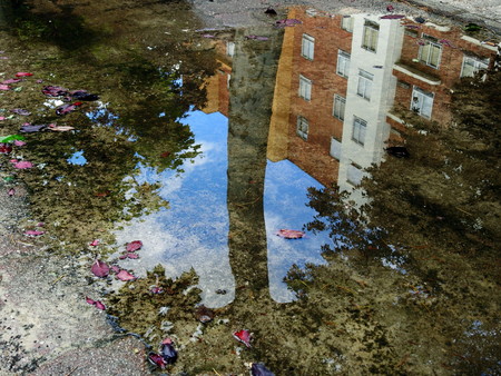 The city reflected in a puddle of water after the rainの写真素材