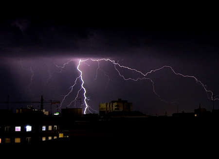 City at night with a big thunder and lightning storm over itの写真素材