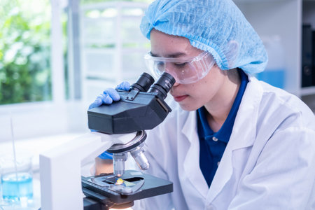 Professional female chemist technician looking microscope research discovery laboratory biotechnology microbiology virus analyzing test, adult woman doctor scientist examining healthcare and medicineの写真素材