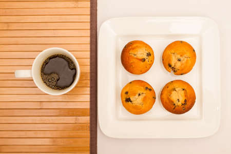 Vanilla with chocolate chips Muffins on a white plate with  a cup of coffeeの写真素材