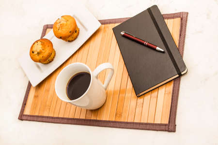 Vanilla with chocolate chips Muffins with  a cup of coffee meanwhile taking notesの写真素材