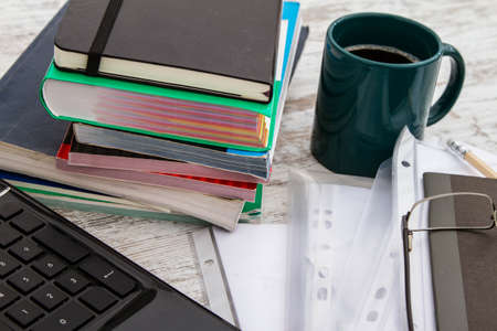 Working, with the laptop, a pile of books, and drinking a coffeeの写真素材