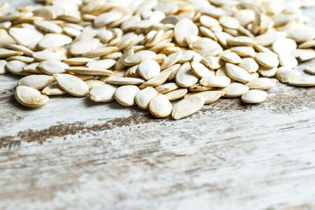 Many pumpkin seeds on a wooden table, backgroundの写真素材