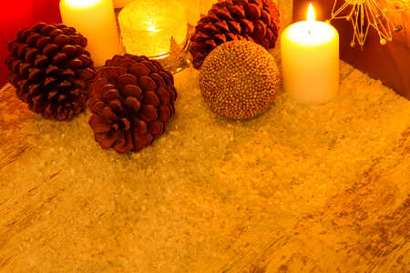 Wooden Christmas background with candles, pine cones, shopping bags and baubles.の写真素材