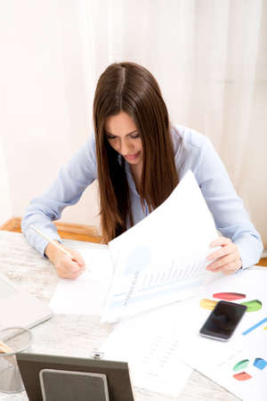 Businesswoman working at the office with the laptop and some documentsの写真素材
