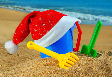 Children's toys and Santa Claus cap on the beach against a blue oceanの写真素材