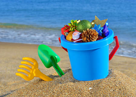 Christmas decorations and children's toys on the beach against a blue oceanの写真素材