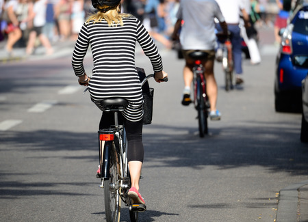 Blonde woman with helmet on bike in trafficの写真素材