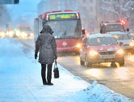 Commuters waiting for arriving bus in snowstormの写真素材