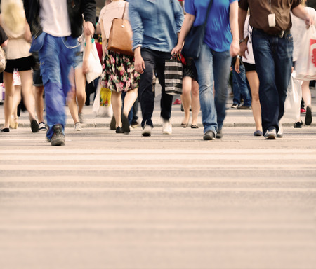 Motion blurred pedestrians crossing sunlit streetの写真素材