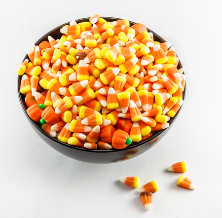 A black bowl over filled with Candy Corn taken on a white background.の写真素材