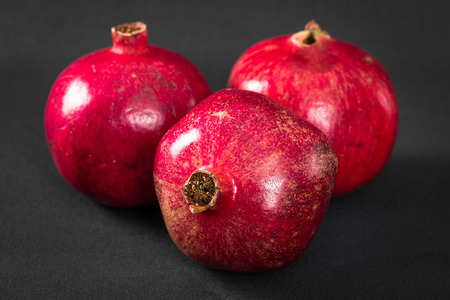 Three ripe pomegranates on a black backgroundの写真素材