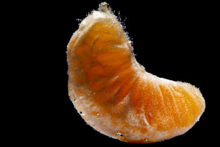Mandarin slice under water isolated on black backgroundの写真素材