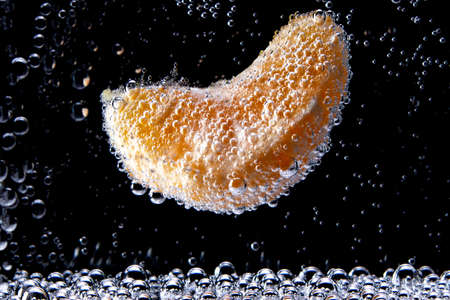 A slice of mandarin in sparkling waterの写真素材