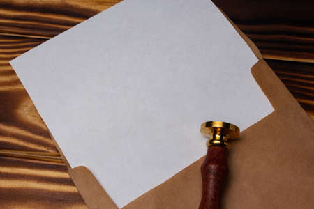 Empty sheet of paper in the envelope and stamp on wooden background