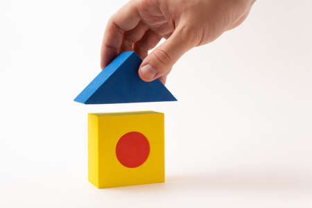 Construction of the house, the hand puts the roof on the house